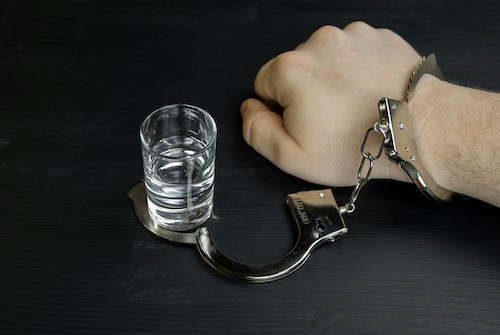 Addiction Concept With Hand Handcuffed to Shot Glass