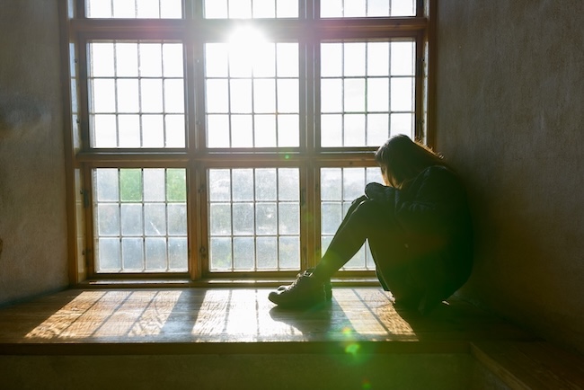 Person sitting alone looking distressed, representing someone who may need inpatient drug treatment