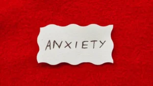An illustration showing the term anxiety, the physical symptoms of anxiety disorders, including chest pain and muscle tension, as they relate to co-occurring anxiety and substance misuse disorders.